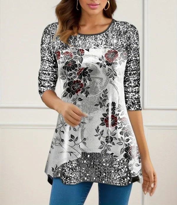 Woman wearing a floral and sequin top with blue jeans against a white background
