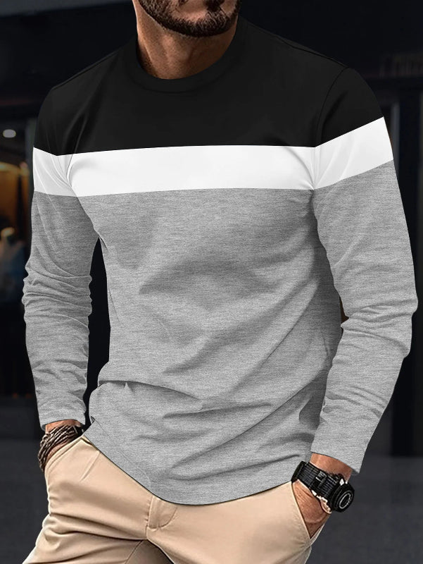 Man wearing a black, gray, and white long-sleeve shirt with beige pants.