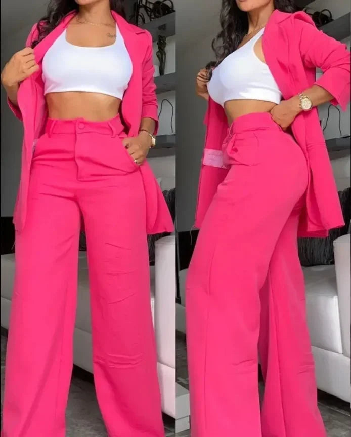 Woman wearing a bright pink suit with a white top in an indoor setting.