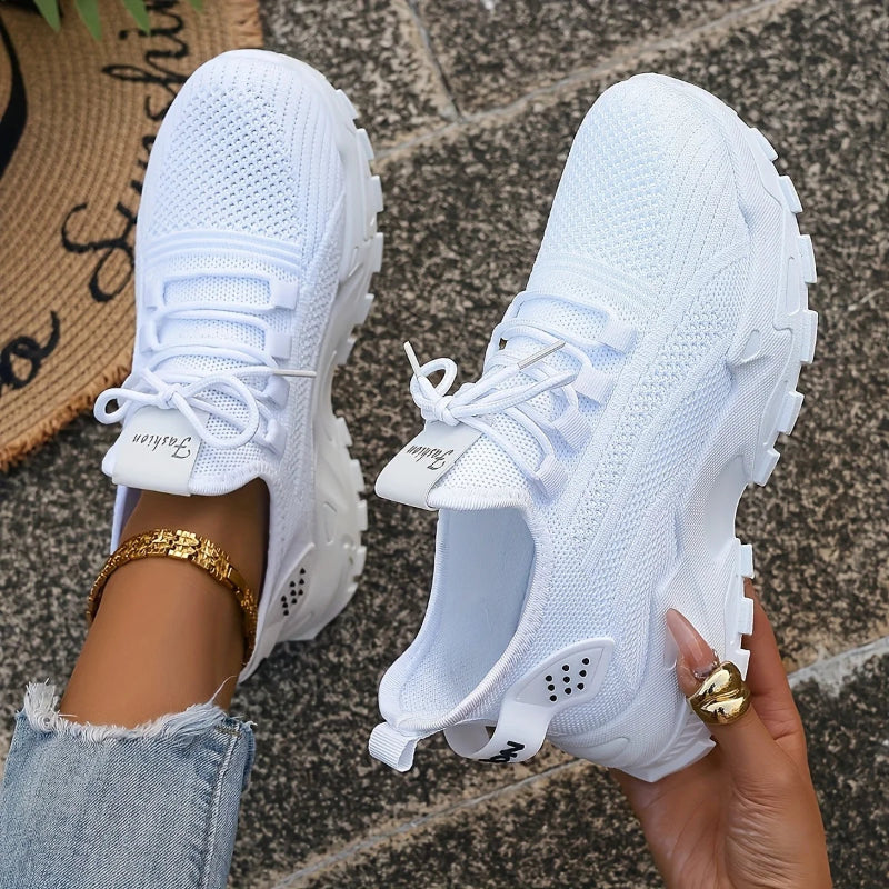 White sneakers held by a person on a textured surface