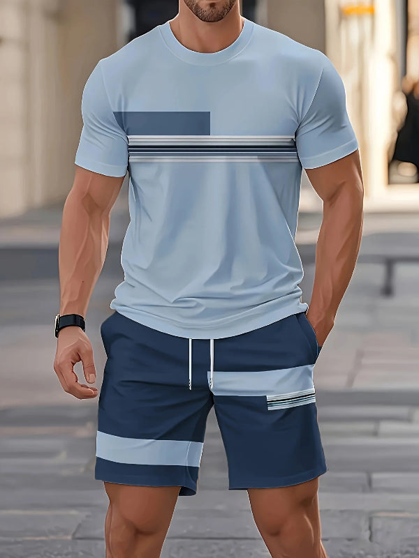 Man wearing a light blue t-shirt and navy shorts with white stripes on a blurred street background