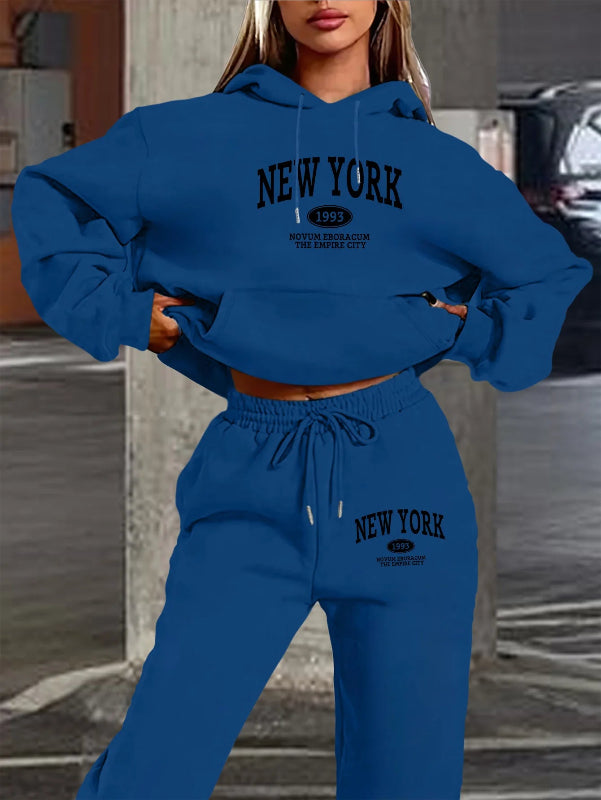Person wearing a blue 'New York' hoodie and sweatpants set in an urban setting.