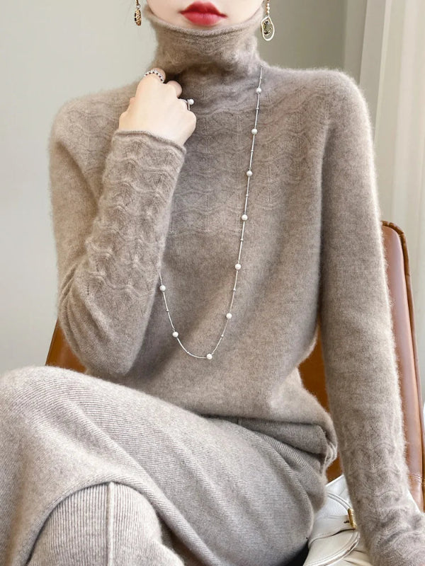 Person wearing a gray turtleneck sweater with a long pearl necklace.