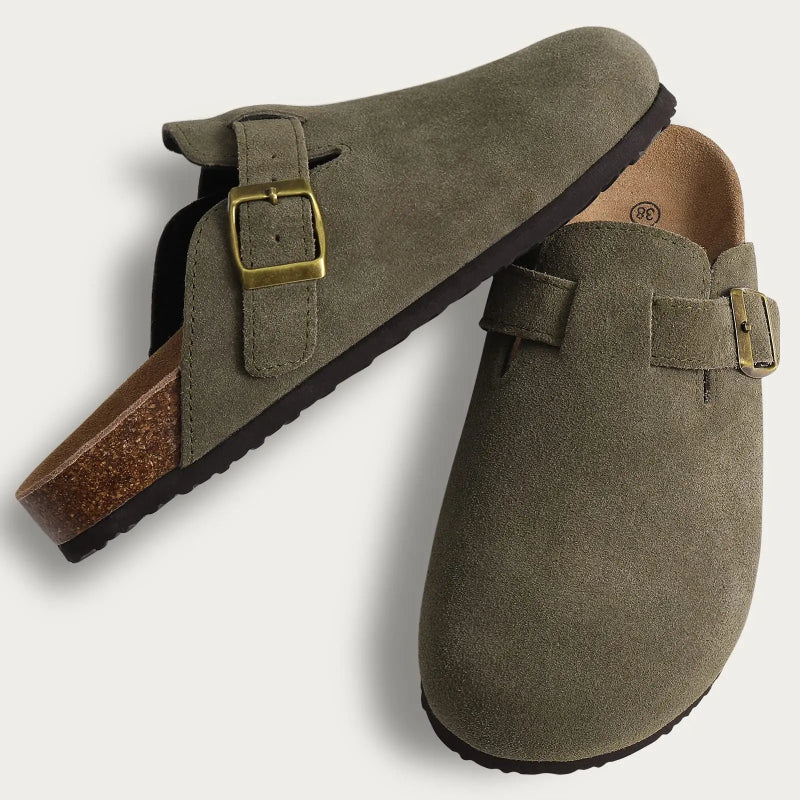Pair of green suede clogs with buckles on a light gray background