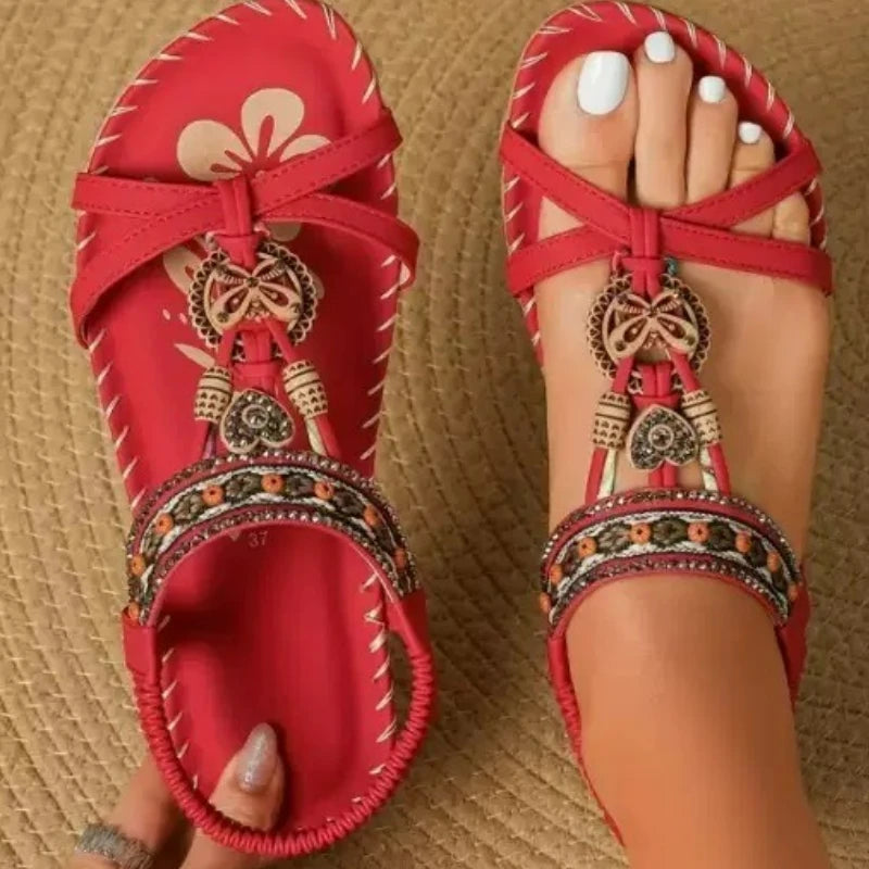 Red sandals with decorative straps on a textured surface