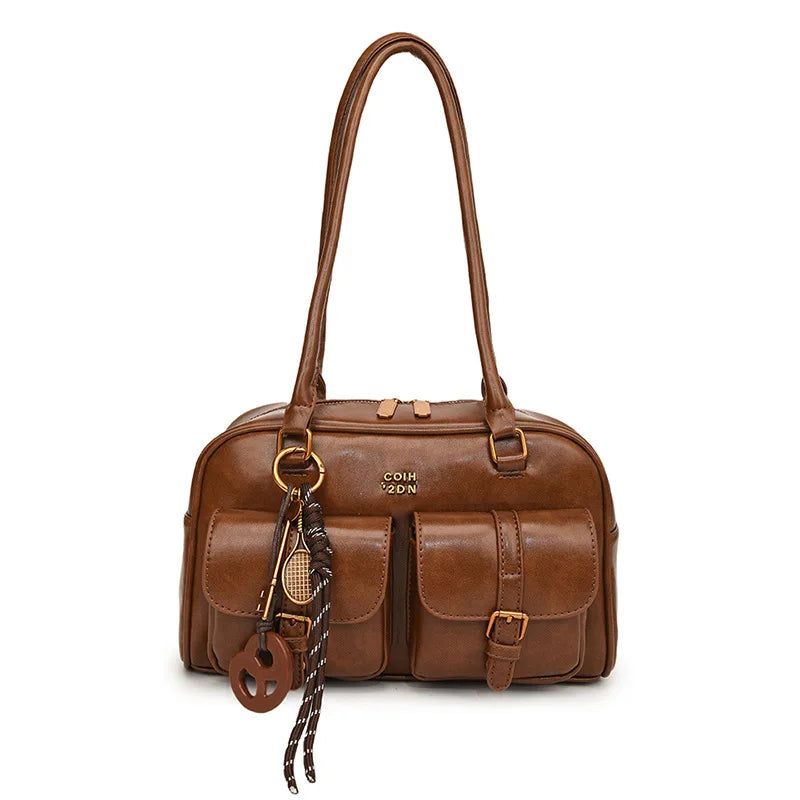 Brown leather handbag with decorative straps on a white background