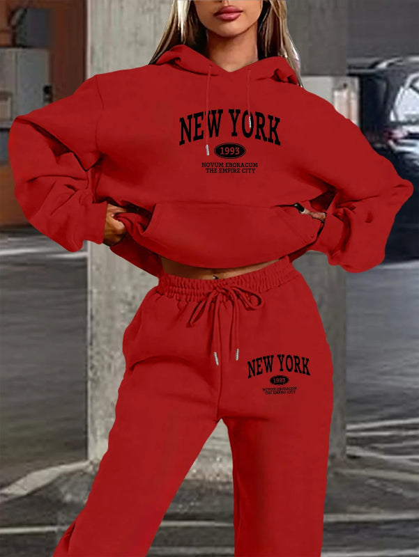 Person wearing a red 'New York' hoodie and sweatpants set in an urban setting.