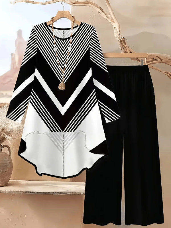 Black and white geometric-patterned top and black pants on a hanger against a neutral background.