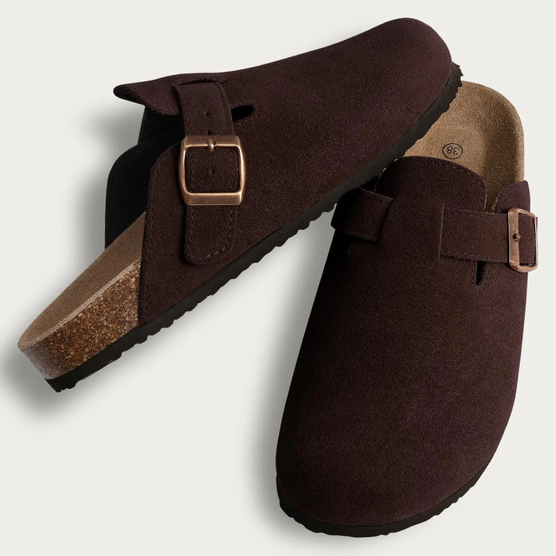 Brown suede clogs with buckles on a light gray background