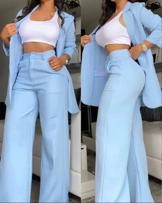 Woman wearing a light blue suit with a white top in an indoor setting.