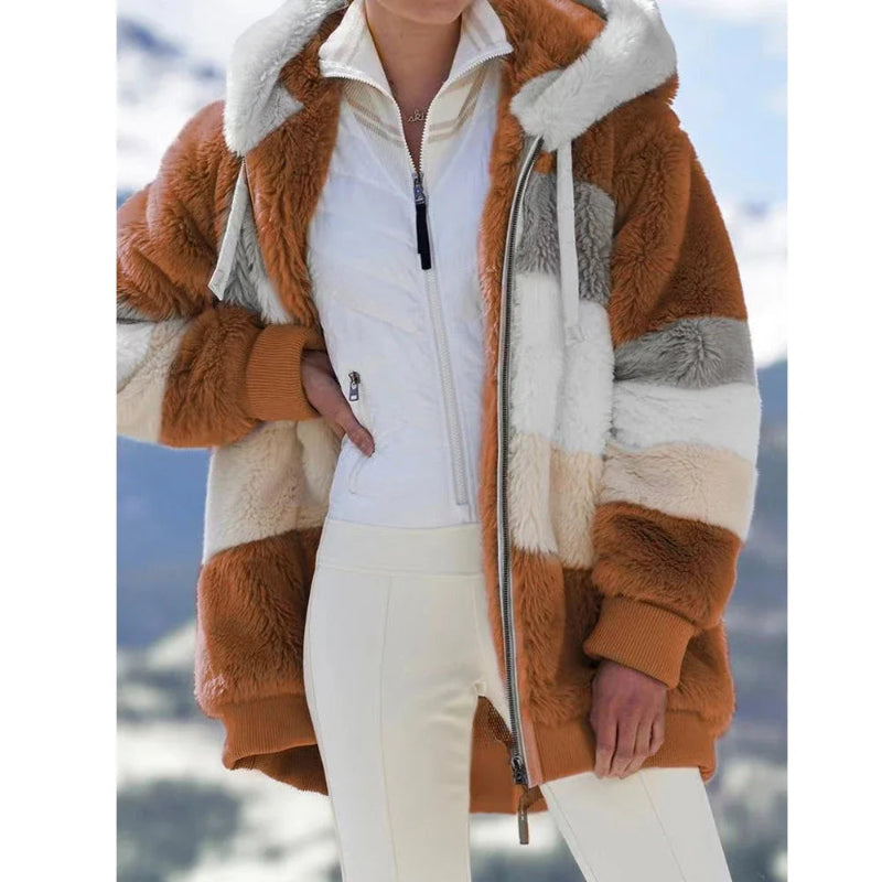 Person wearing a brown and white sherpa jacket with a blurred snowy background