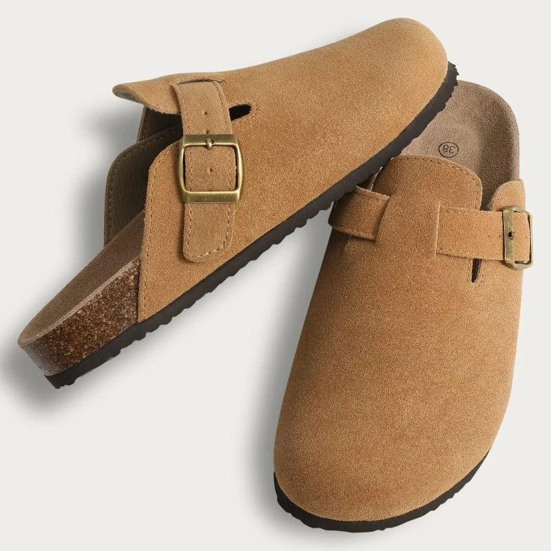 Pair of tan clogs with buckles on a light gray background