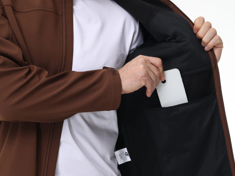 Person holding a black jacket with a white tag, wearing a brown coat and white shirt.