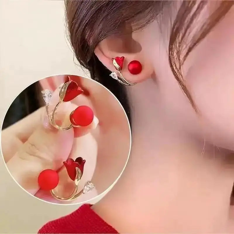 Red earrings with gold accents worn by a person, close-up view.