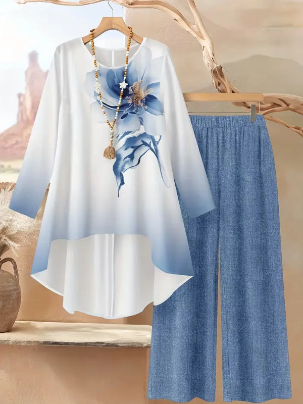 White top with blue floral design and blue pants on a hanger against a neutral background