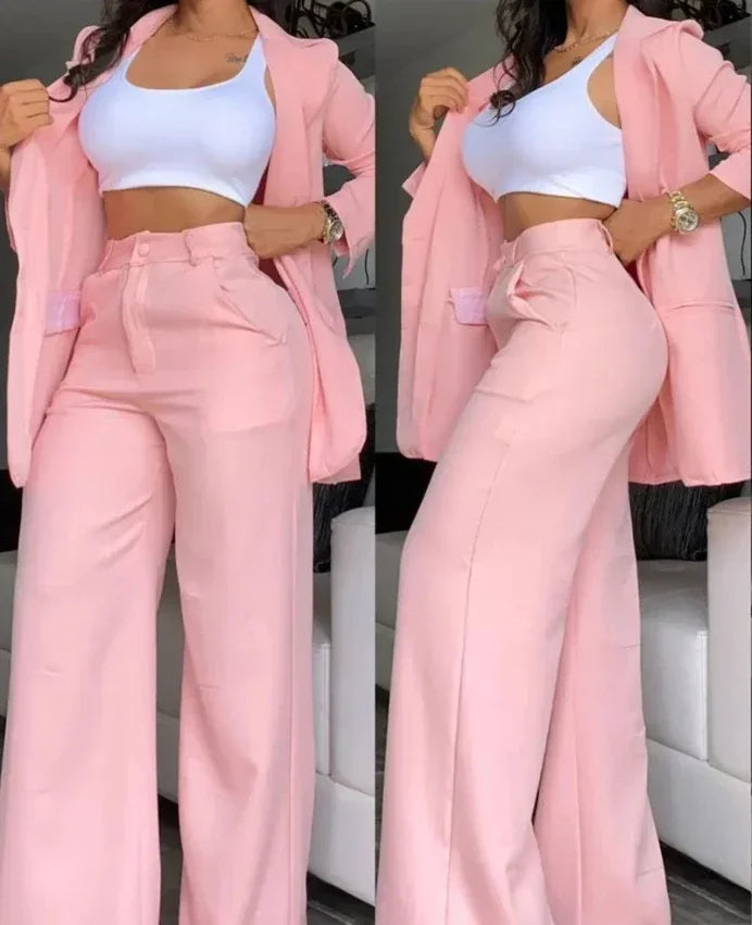 Person wearing a pink outfit with a white top and pants, standing against a neutral background.