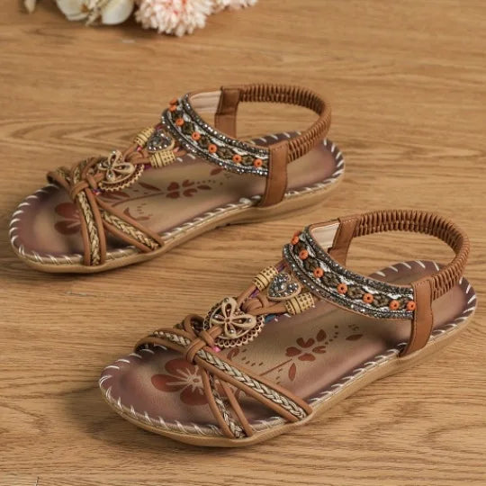 Pair of brown sandals with decorative straps on a wooden surface