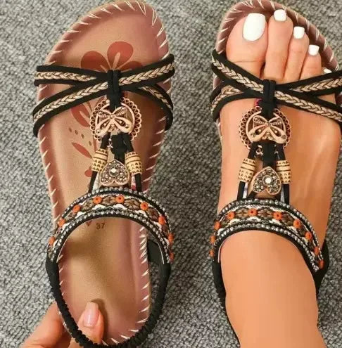 Pair of embellished sandals with decorative straps on a textured surface