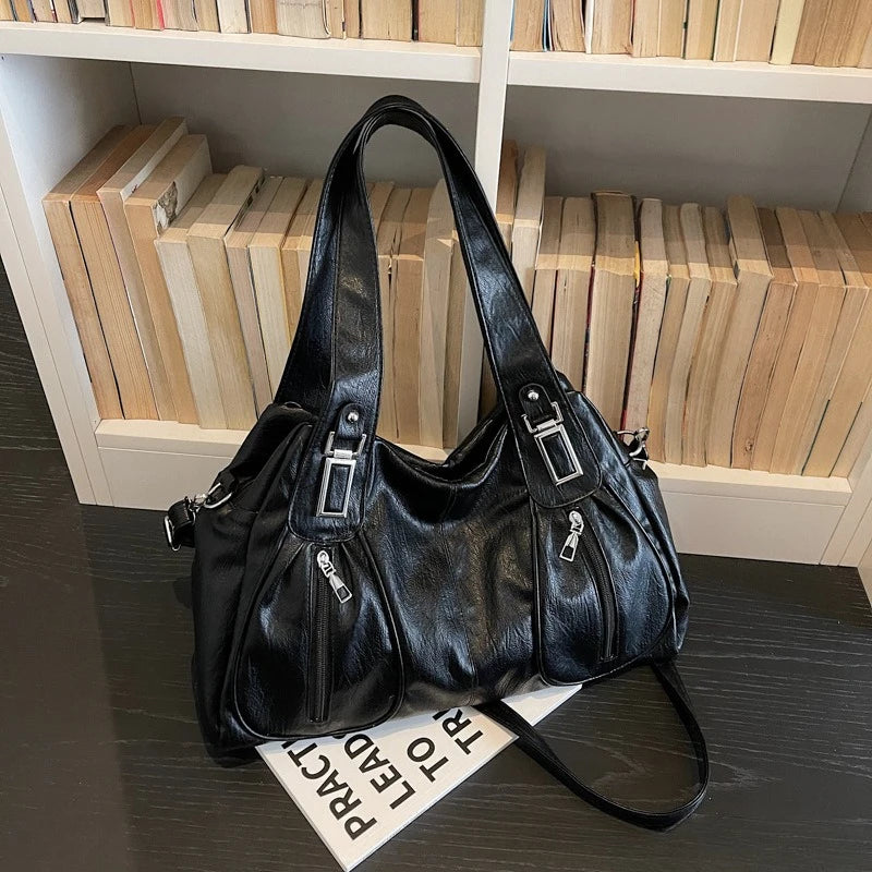 Black handbag on a dark surface with a bookshelf in the background