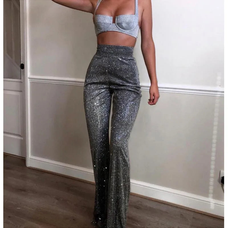 Person wearing sparkly silver pants and top in a room with wooden floor and white walls.