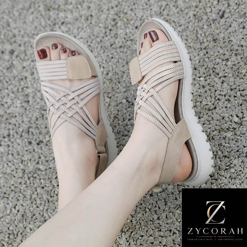 A pair of women's platform sandals with woven beige straps and a thick white sole, shown being worn on feet against a gray gravel background. A ZYCORAH brand logo is visible in the bottom right corner.