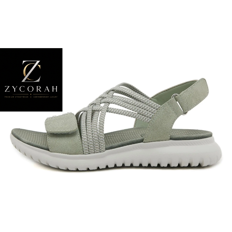 A light sage green strappy sandal with a thick white sole, shown in a side profile on a white background. A black square logo for 'Zycorah' is visible in the top-left corner.