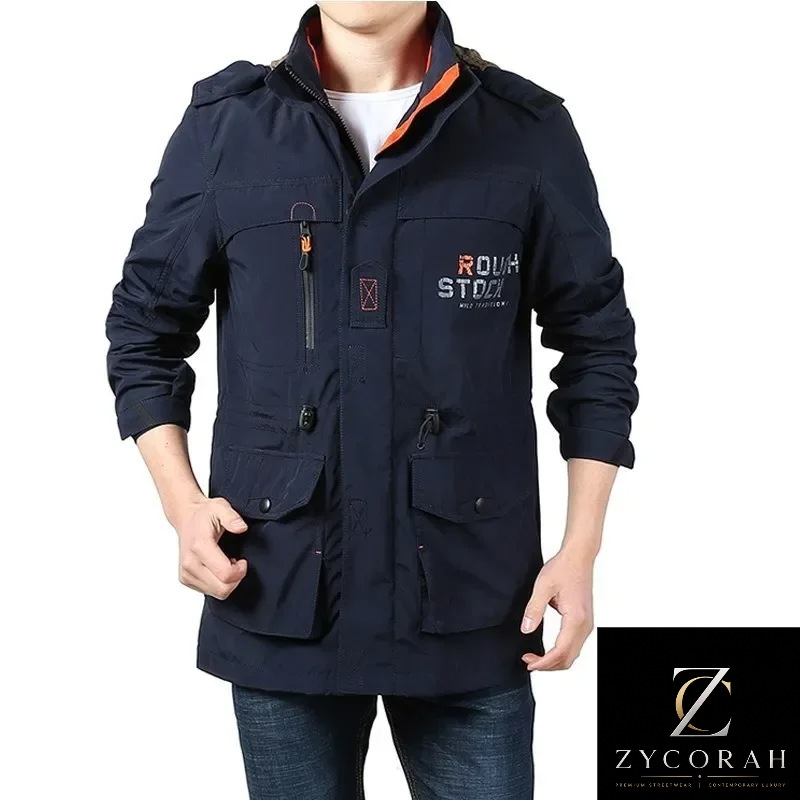 A man wearing a dark navy blue utility jacket with multiple pockets, zippered details, and a visible 'ROUGH STATION' logo on the left chest, paired with a white undershirt and blue jeans. A ZYCORAH brand logo is visible in the bottom right corner.