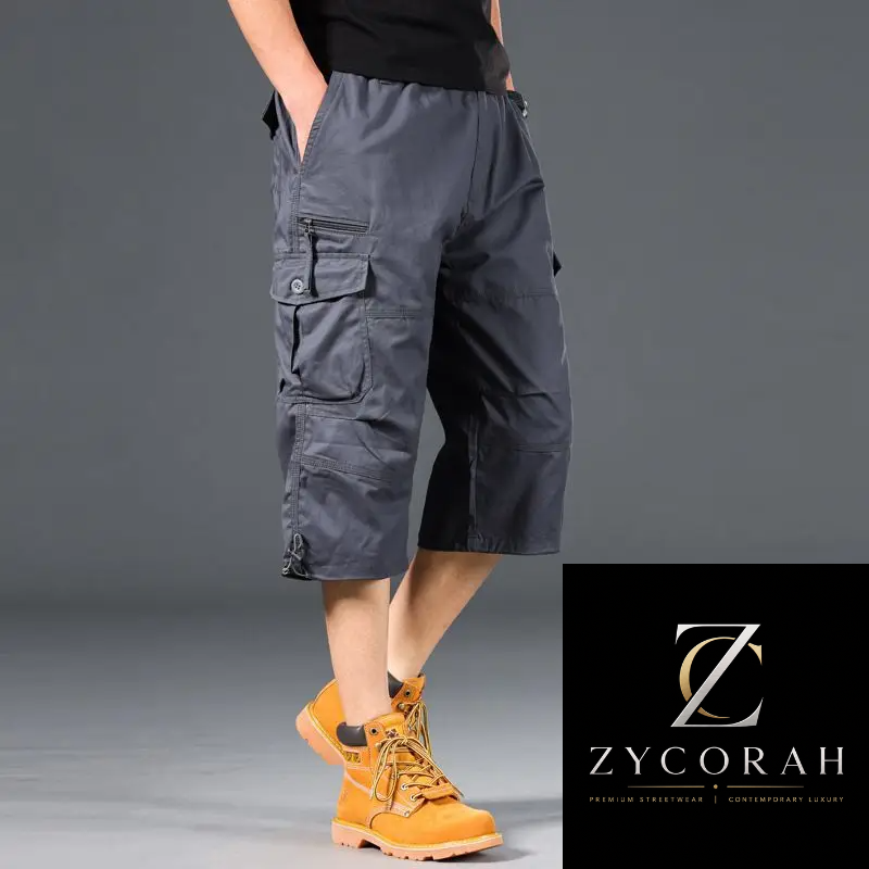 A model wearing dark gray cargo shorts with multiple utility pockets and yellow hiking boots, shown from the waist down against a gray studio background. A black brand overlay in the bottom right corner displays the Zycorah logo.