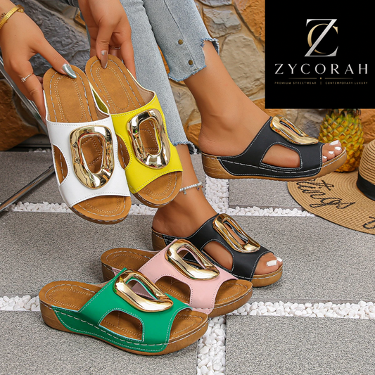 Four women's slide sandals with large metallic buckle details are shown in multiple colorways: white, yellow, black, green, pink, and black. The sandals are being held by a model wearing light blue jeans, with a stone wall and outdoor props in the background.