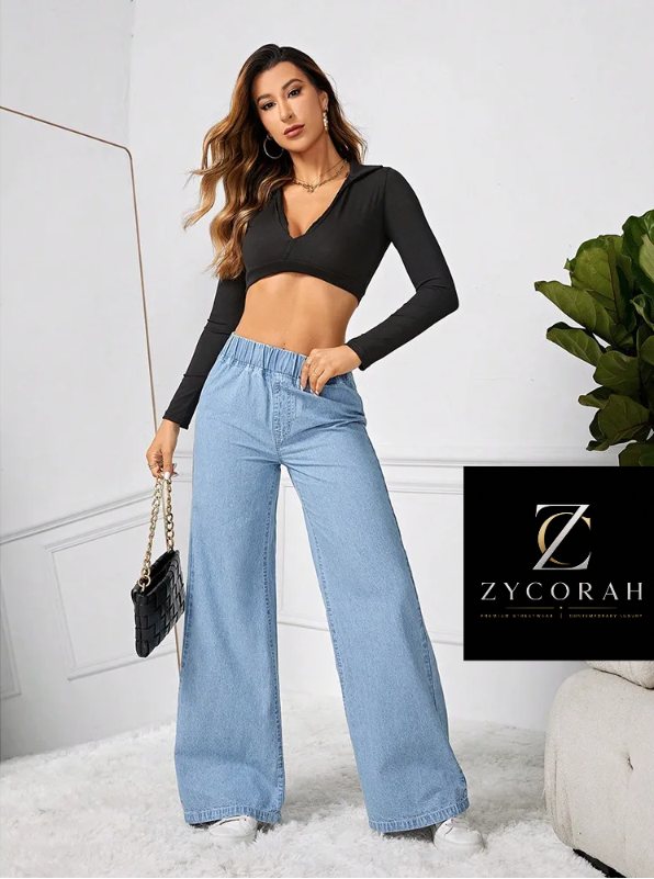 A woman models a black long-sleeve crop top and light blue wide-leg jeans in a bright indoor setting. A black brand card for ZYCORAH is displayed on the right side of the image.