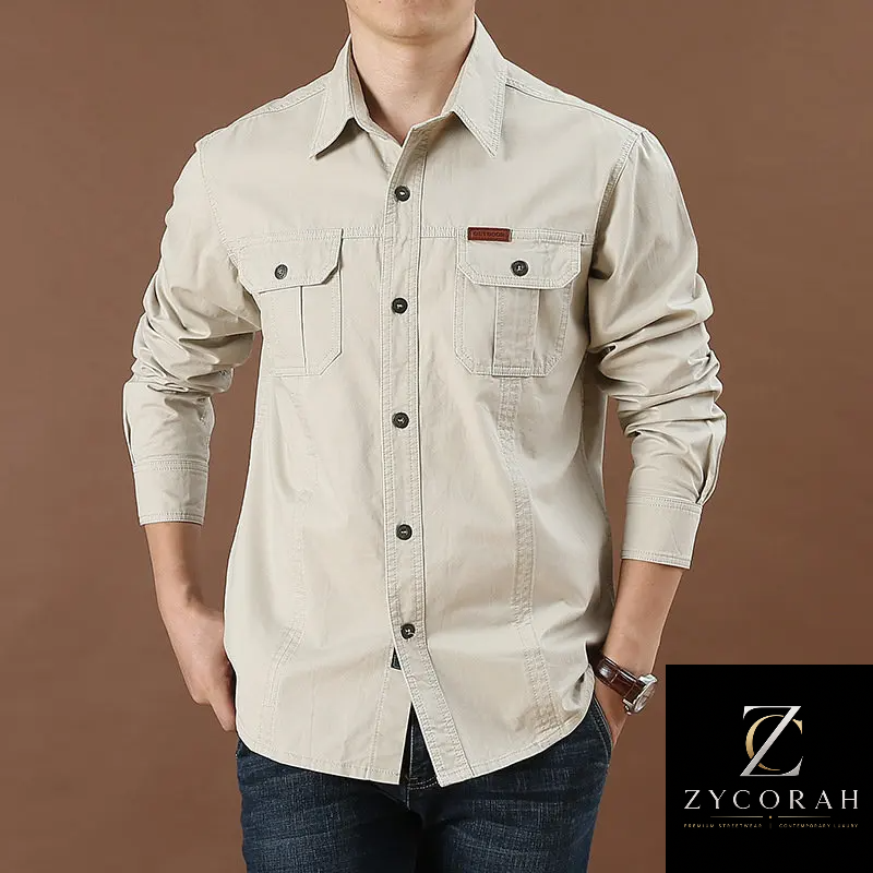 A man wearing a light beige long-sleeve button-up shirt with two chest pockets and dark buttons, paired with dark blue jeans, against a solid brown background. A ZYCORAH brand logo is visible in the bottom right corner.