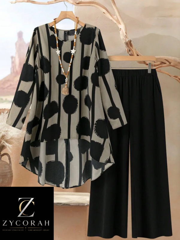 A women's two-piece outfit set from Zycorah, featuring a long-sleeve tunic top with a black and gray abstract polka dot and stripe pattern, paired with solid black wide-leg pants. The set is displayed on hangers with a wooden hanger and a decorative necklace.