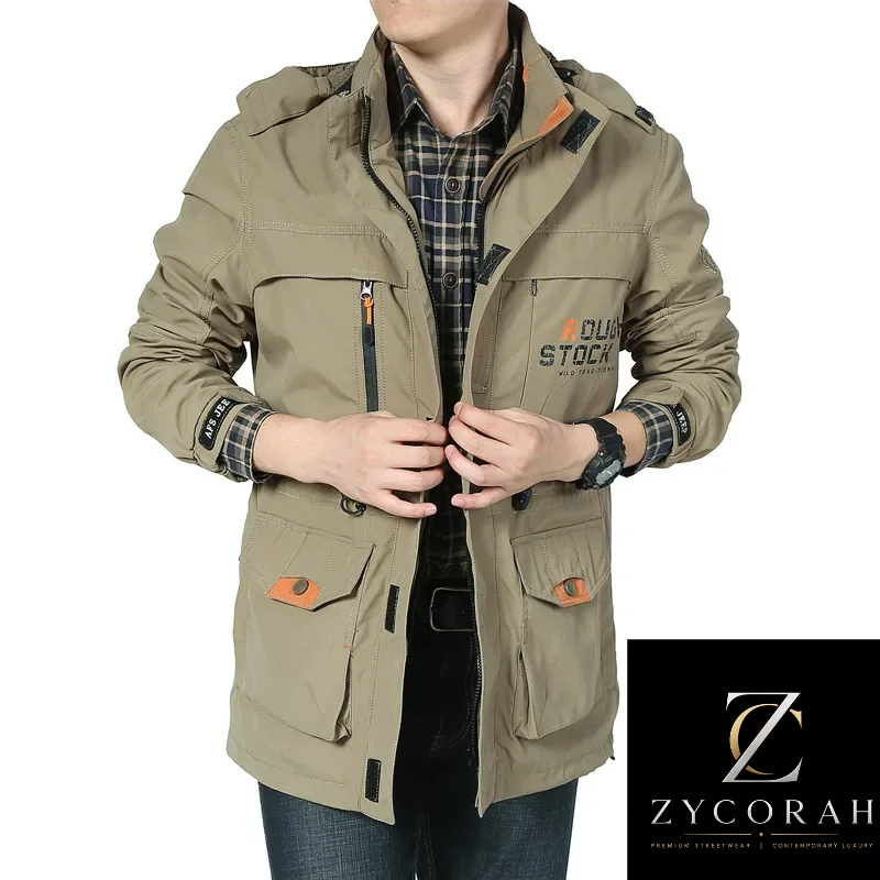 A man wearing a beige outdoor jacket with multiple pockets, zippers, and orange accents, layered over a plaid shirt and jeans. The Zycorah brand logo is visible on the jacket and in a black box at the bottom right.